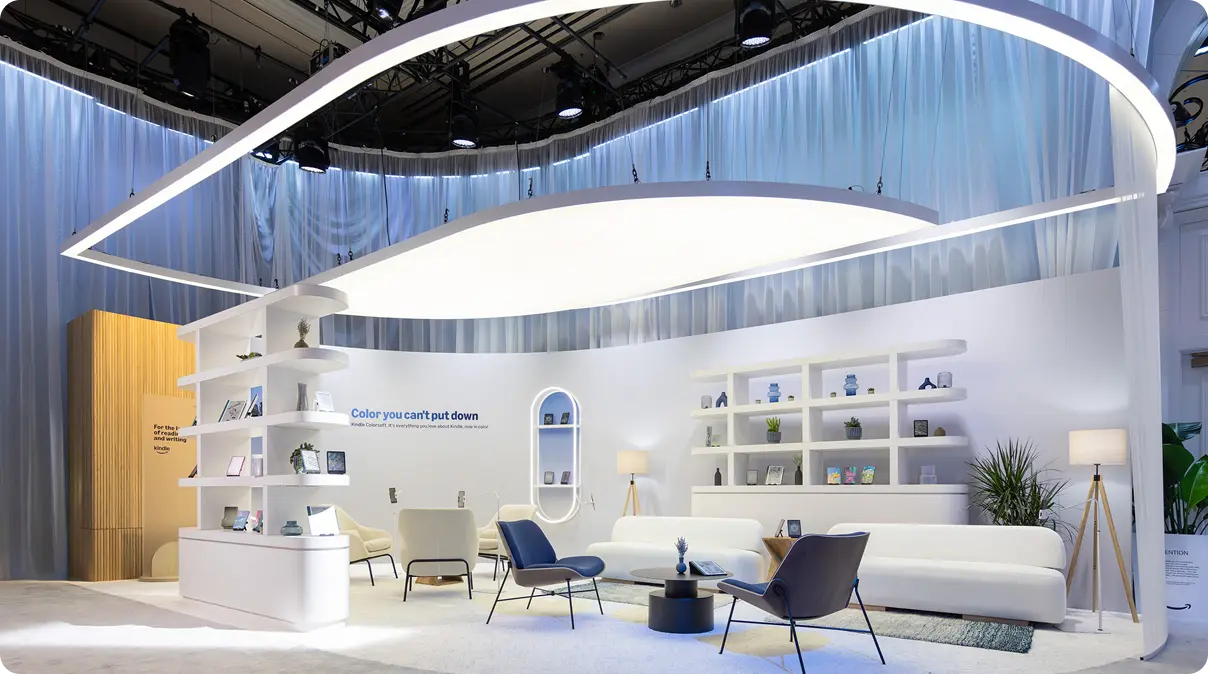 Trade show booth with curved white sail-like ceiling element above a modern lounge area