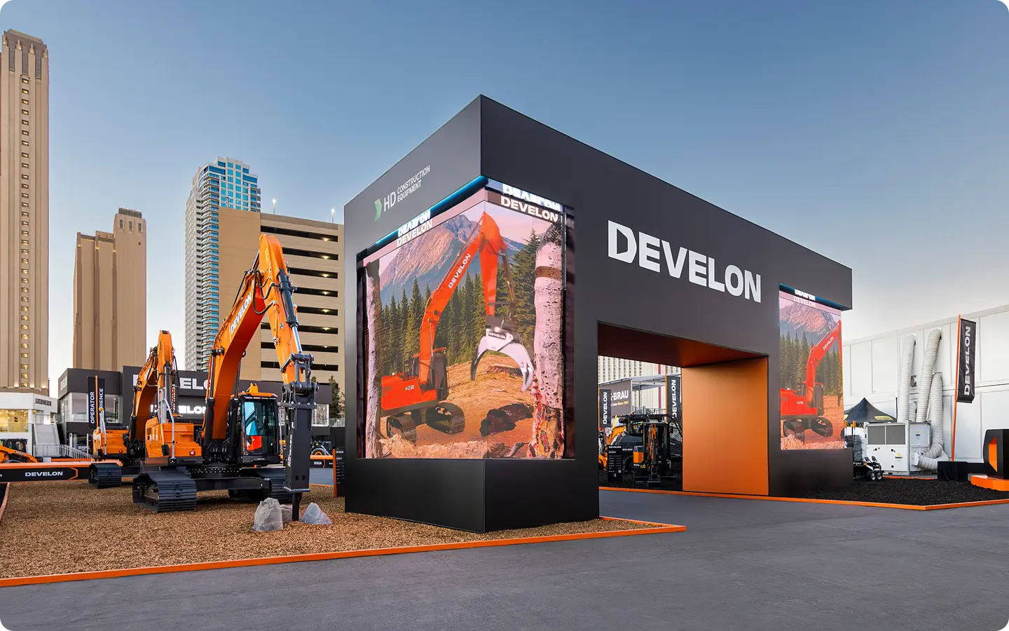DEVELON outdoor trade show booth with construction excavators and large LED video walls